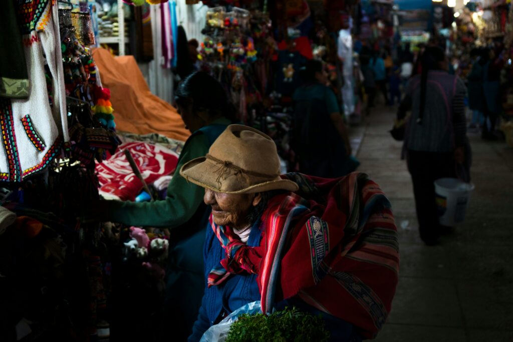 pexels-photo-22484295-22484295 Elderly woman shopping at a vibrant market in Cusco, Peru.