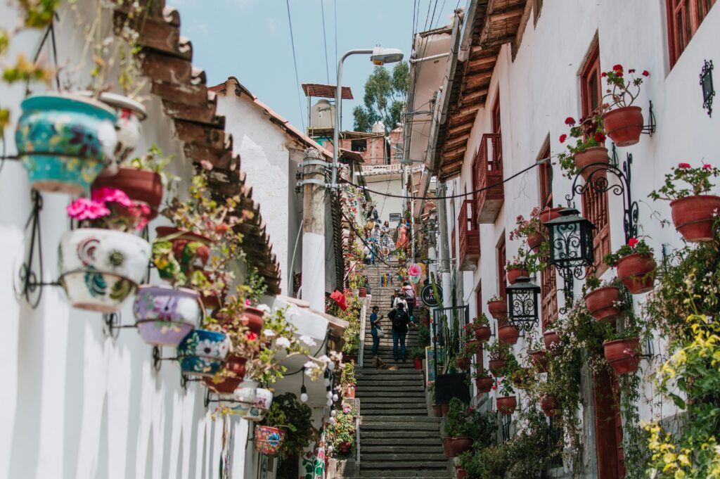 pexels-photo-33027860-33027860 Vibrant street in Cusco with colorful flower pots and traditional architecture, inviting exploration.