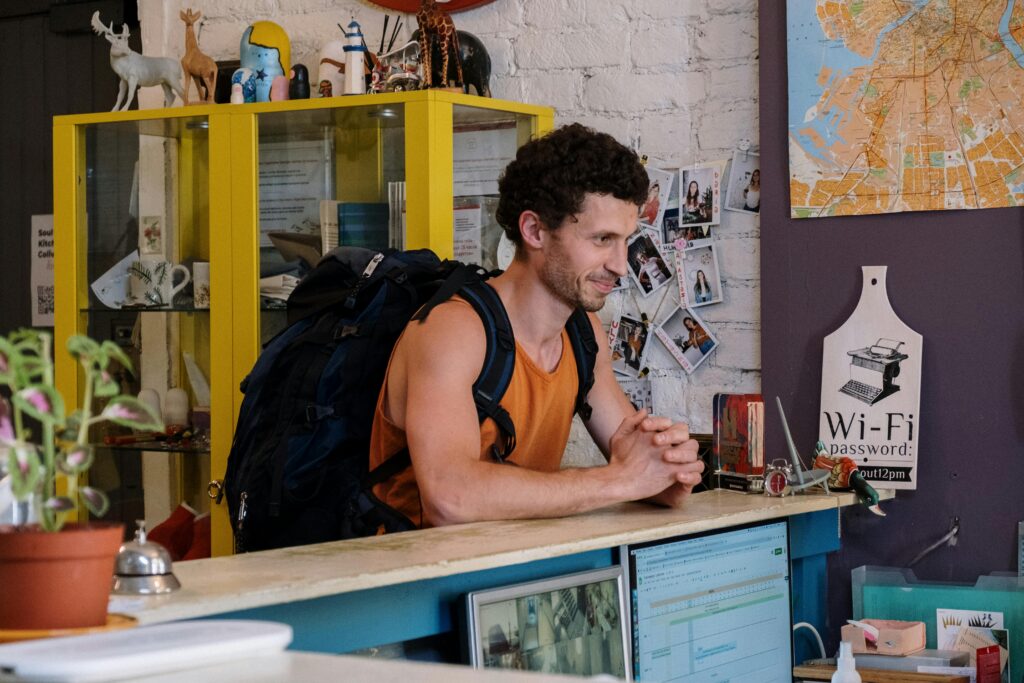 pexels-photo-5137966-5137966 A backpacker checking into a cozy hostel with vibrant decor and friendly atmosphere.